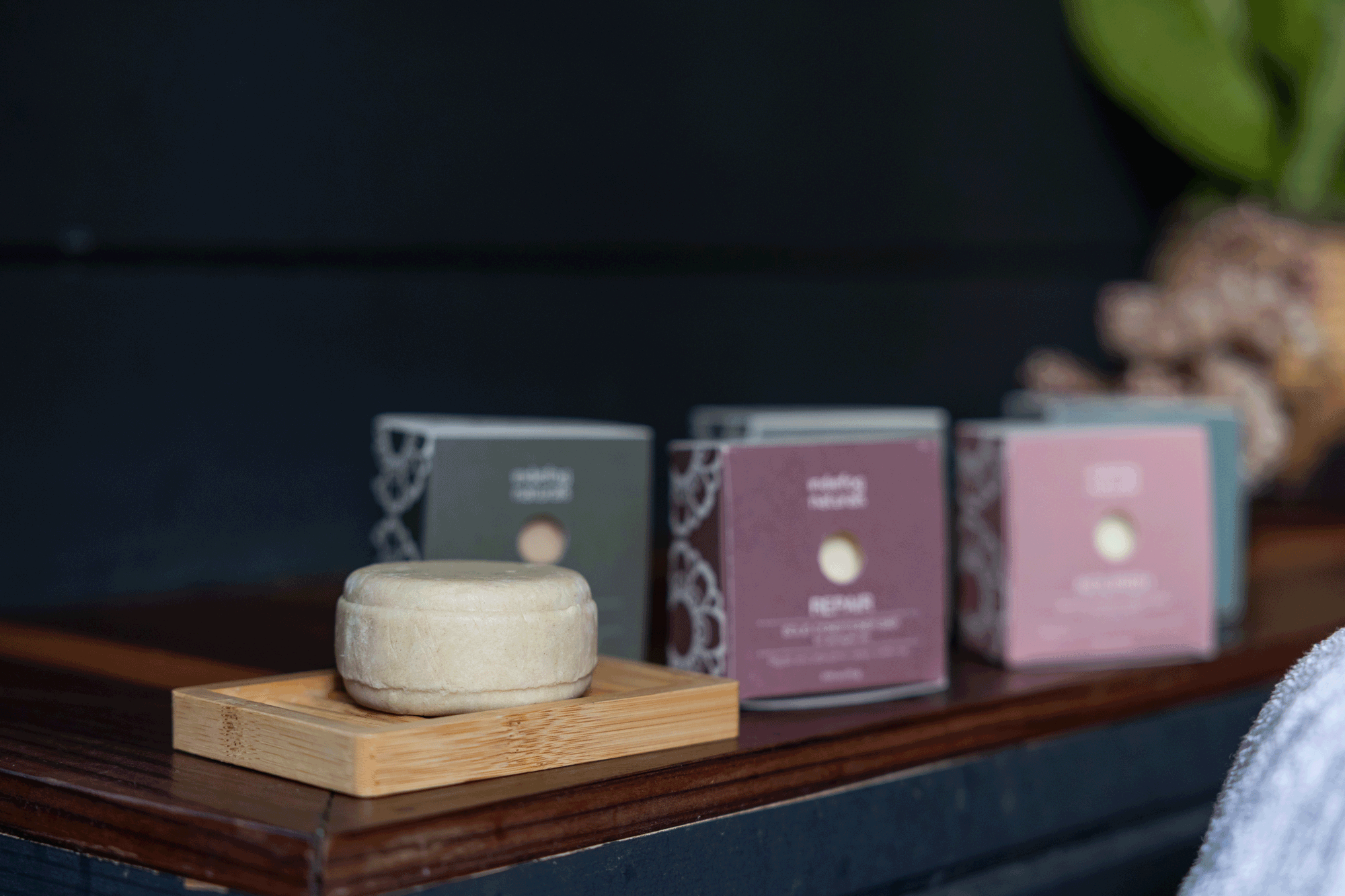 A pale round bar resting on a bamboo draining dish, with a row of Indiefog bar cartons behind it.