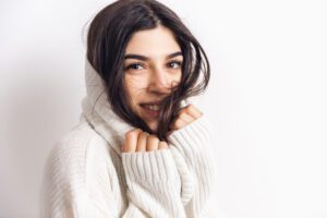 Wrapping. Portrait of beautiful brunette woman in comfortable soft longsleeve isolated on white studio background. Home comfort, emotions, facial expression, winter mood concept. Copyspace.
