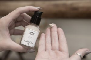 Applying Indiefog Vitamin C Mineral Brightening Elixir with pump bottle onto hand for daily skin support